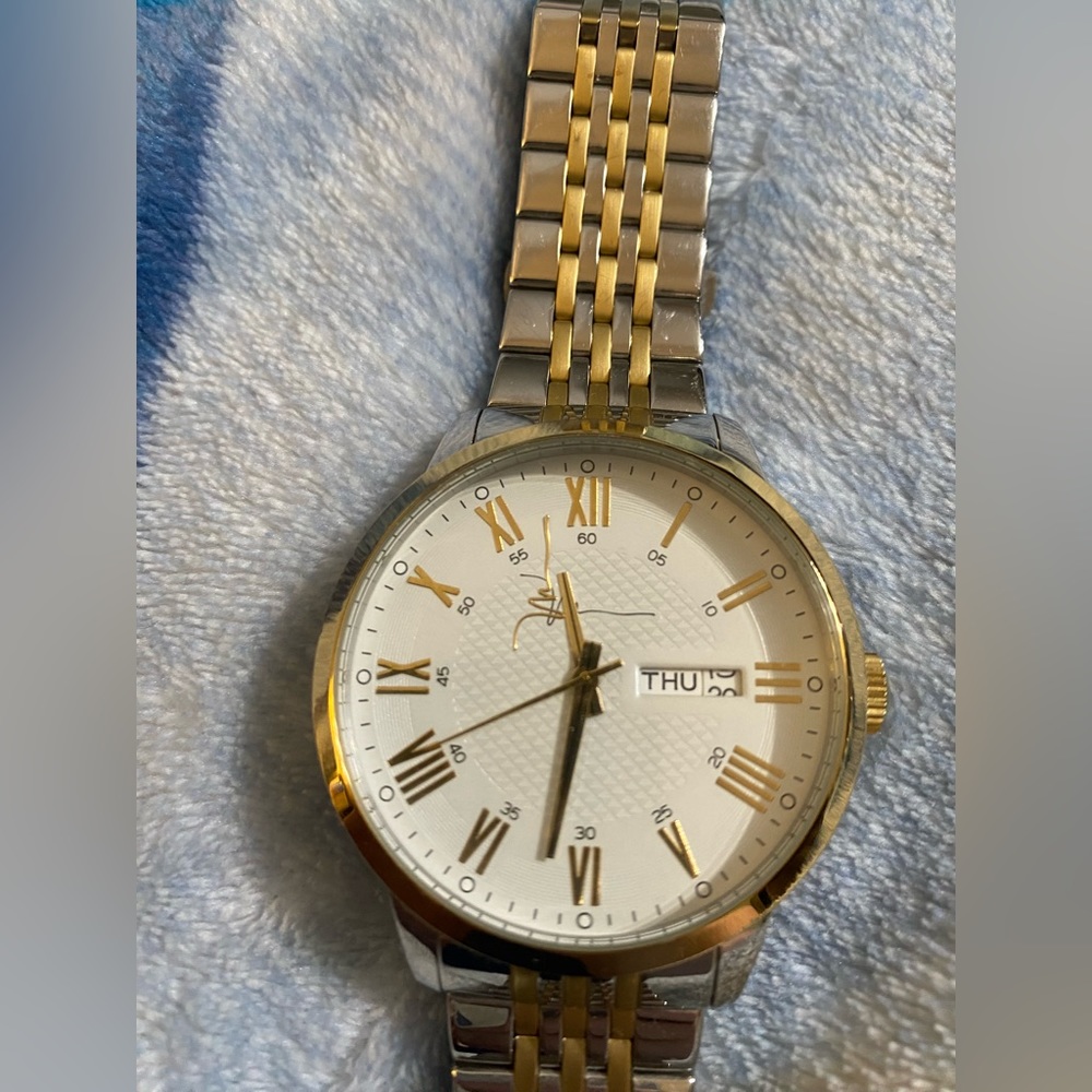 This is a stainless steel men’s watch with gold accents.